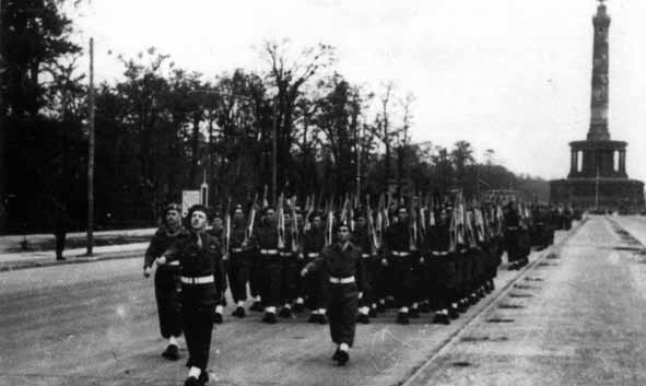 131st Brigade HQ and Signals Squadron marching towards the saluting dias, during Victory Parade. Leading this detachment is Captain Gordon Pelmore, R.Signals followed by Capt. Wadham and Lieut. J.F.C.(Joe) Rodrigues (centre of picture)